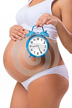 Pregnant belly with alarm clock. Conceptual image of happy pregnancy.