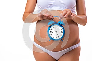 Pregnant belly with alarm clock. Conceptual image. Soon birth.