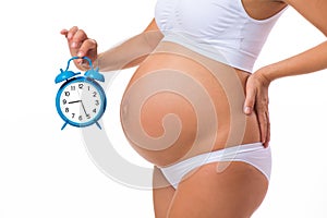 Pregnant belly with alarm clock. Conceptual image. Soon birth. Fetal development by months
