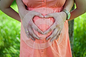 Pregnant Belly with fingers Heart symbol.