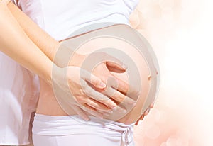 Pregnant belly with hands of mother and father