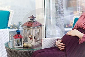 Pregnant belly and lanterns. Christmas holyday decor photo