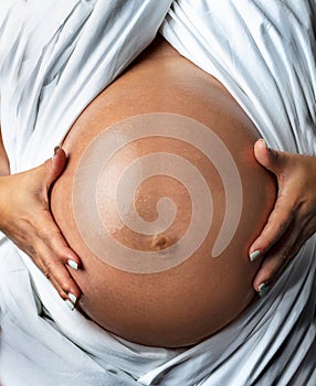 Pregnant belly oiled with white sheet
