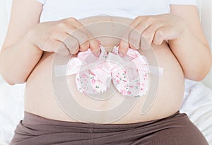 Pregnant belly with a pair of pink shoes