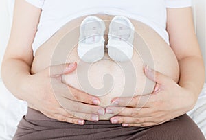 Pregnant belly with a pair of white shoes