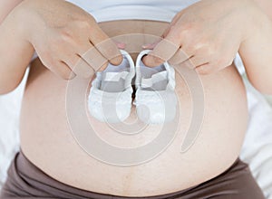 Pregnant belly with a pair of white shoes