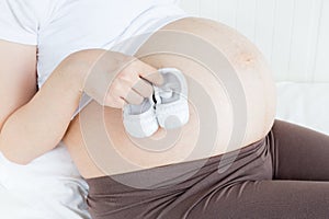 Pregnant belly with a pair of white shoes