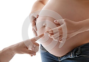Pregnant Belly with Parents Hands. Father showing Finger on Pregnancy Belly Button. Couple expecting Baby Birth. Human Creation