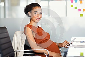 Pregnant black businesswoman using phone at office while working