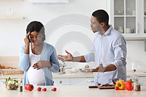 Pregnant black woman fighting with her husband while cooking together
