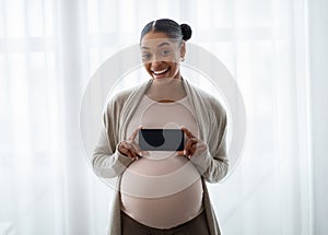 Pregnant black woman showing blank smartphone screen