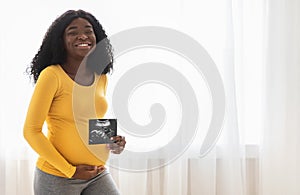 Pregnant black woman showing her baby sonography