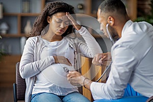 Pregnant black woman suffering from migraine, visiting doctor