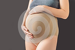 Pregnant bliss: Mom-to-be embraces her baby bump with a soft fabric bandage, providing gentle support. Maternity made