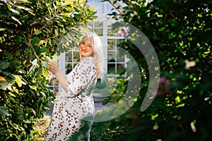 Pregnant blonde in white dress in summer garden