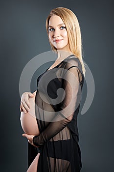 Pregnant blonde woman in black underwear, the last ninth month of pregnancy. Motherhood