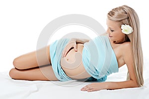 The pregnant blonde woman lays isolated photo