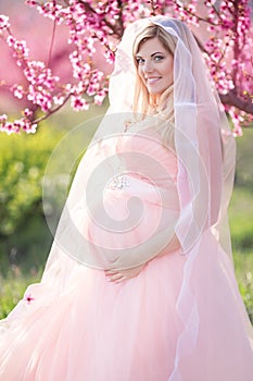 Pregnant bride girl in blossom peach garden