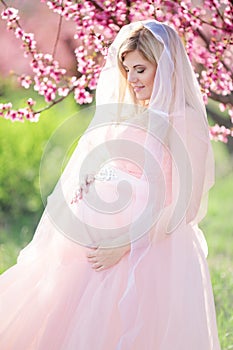 Pregnant bride girl in blossom spring garden