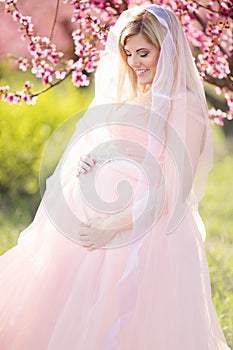 Pregnant bride girl in blossom spring garden
