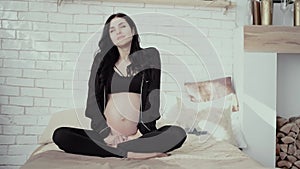 Pregnant brunette with long curly hair sits in special pose