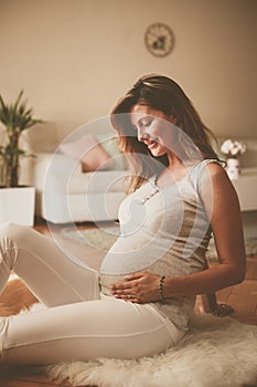 Pregnant brunette woman touching her belly.