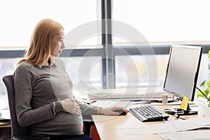 Pregnant businesswoman with computer at office