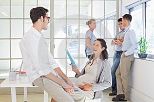 Pregnant businesswoman laughing with colleague