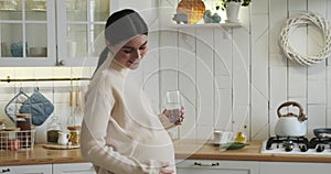 Pregnant Caucasian Woman Embracing Her Belly with Water in Hand