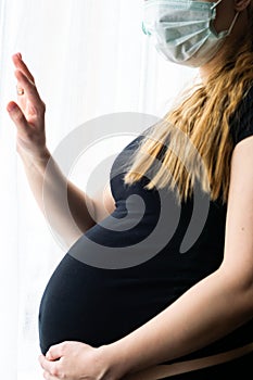 Pregnant caucasian woman wearing a surgical mask to prevent coronavirus contamination during home quarantine in Europe. Coronaviru