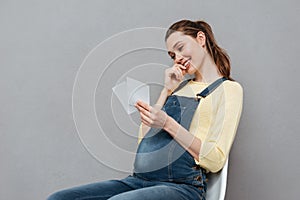 Pregnant cheerful woman holding ultrasound scans