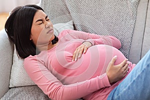 Pregnant Chinese Lady Suffering From Pain Touching Belly At Home