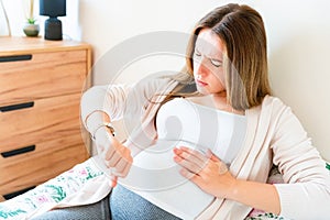 Pregnant contractions time. Pregnancy woman watching clock, holding baby belly. Childbirth time, contractions pain