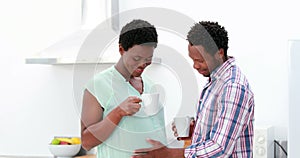 Pregnant couple drinking coffee in the kitchen