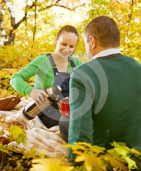 Pregnant couple having picnic in autumn park