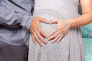 Pregnant couple with heart hands