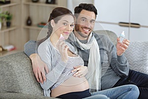 pregnant couple holding blue and pink bottles