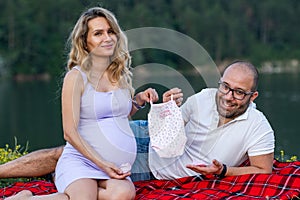 Pregnant couple holding up onesie