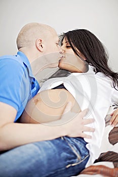 Pregnant couple kissing in bed