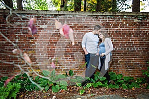 Pregnant couple kissing in front of brick wall