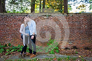 Pregnant couple kissing in front of brick wall