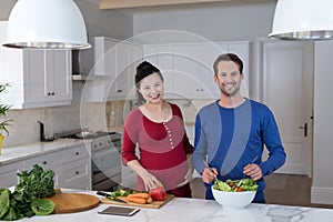 Pregnant couple preparing salad in the kitchen