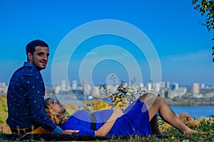 Pregnant couple sitting in the park with city view