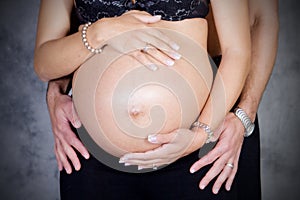 Pregnant couple touching each other with hands on belly.