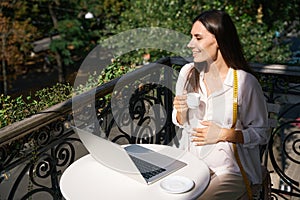 Pregnant craftswoman enjoys a cup of coffee on charming balcony