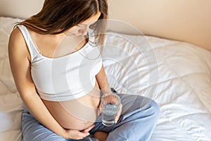 Pregnant drinking water. Young pregnancy mother drink water. Pregnant lady waiting of baby. Glass of water. Concept