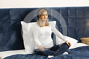 Pregnant female with headphones on head, listens