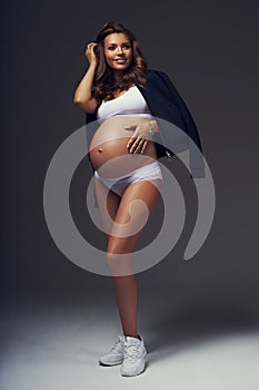Pregnant female model in sports underwear standing and posing
