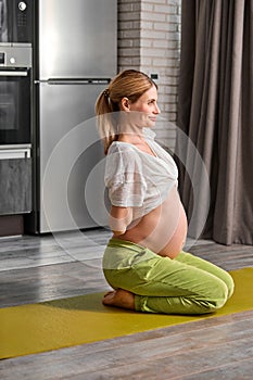 pregnant female tretching body at home, going to do yoga exercises on floor