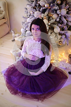 Pregnant girl in a beautiful interior studio celebrates Christmas